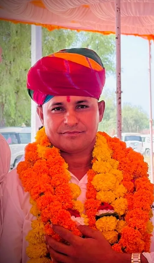 साफ़ा, तिलक और गेंदे की माला पहने मुस्कुराते हनुमानराम पटेल