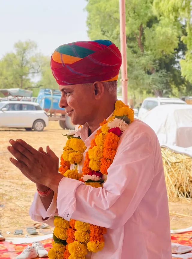 साफ़ा और माला पहने हाथ जोड़कर अभिवादन करते हनुमानराम पटेल (AI से निखारी गई फ़ोटो)