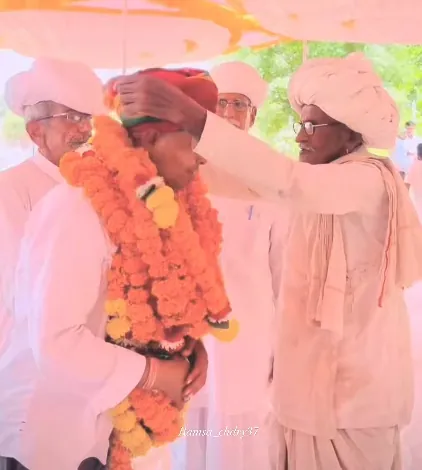 एक बुज़ुर्ग हनुमानराम पटेल को गेंदे की माला पहनाते हुए
